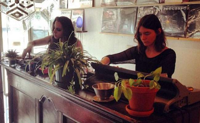 Two people in a room creating live music on a table with many plants